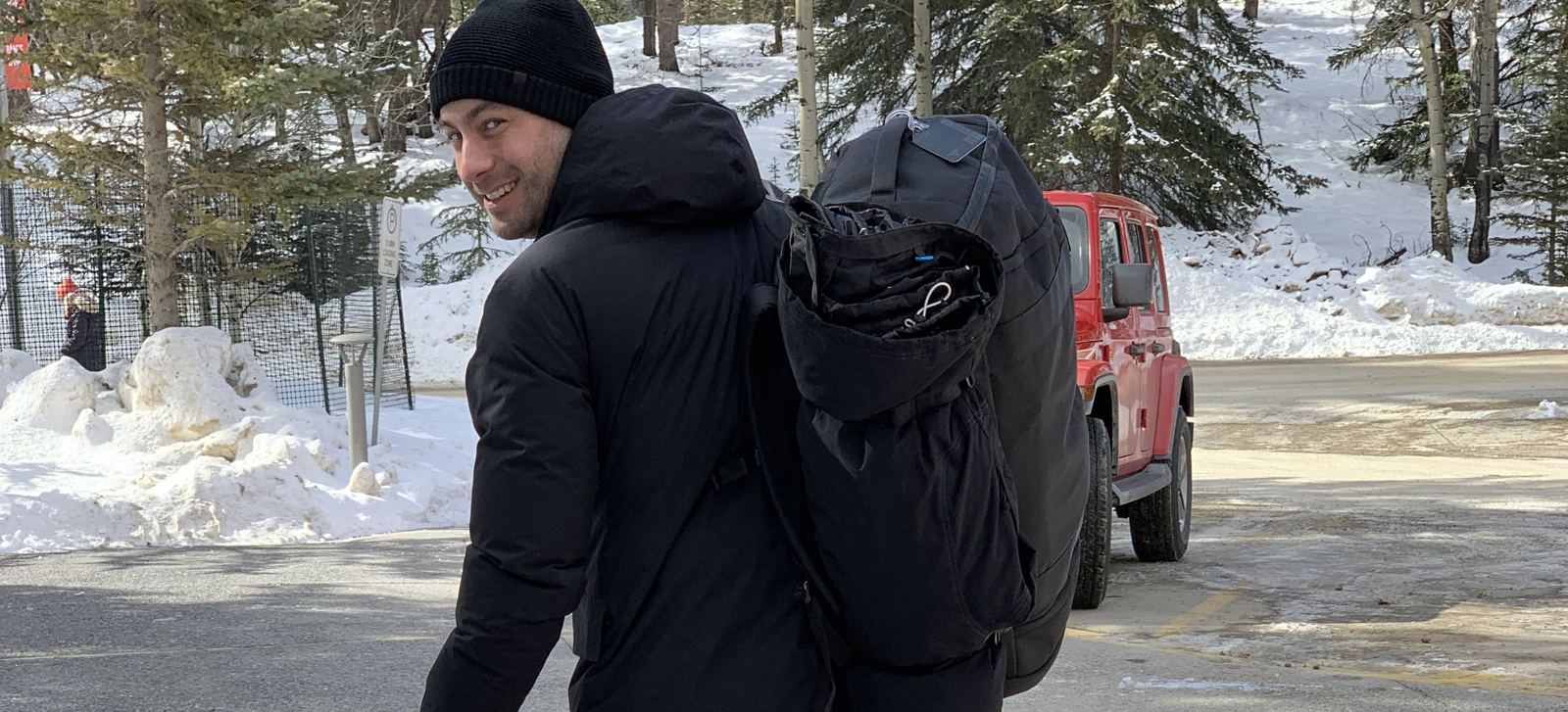 Manny smiling over his shoulder with a large backpack in a snowy mountain town