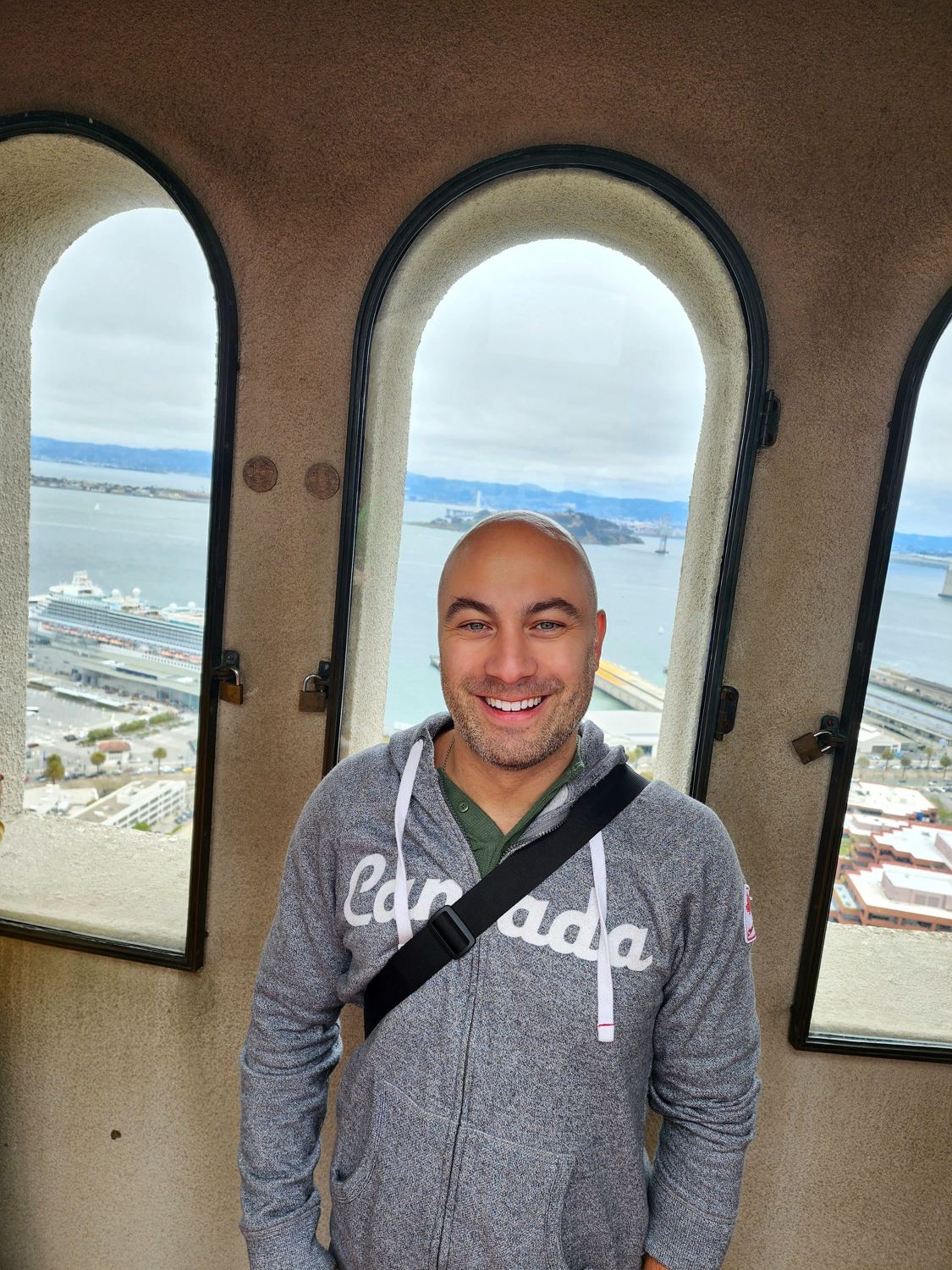 Manny smiling in a Canada hoodie inside a tower with arched windows